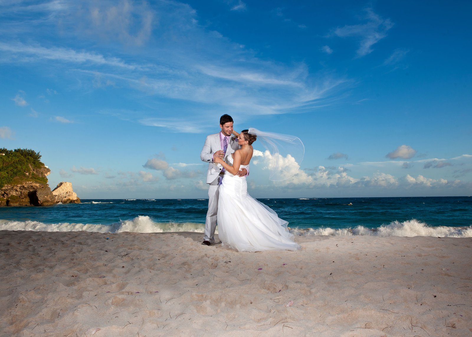 Dramatic image with Bride and Groom at Foul Bay Beach Barbados, as veil blow in the wind